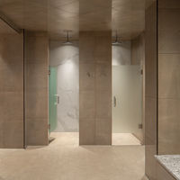 a shower area with glass doored shower stalls and stacks of fresh towels