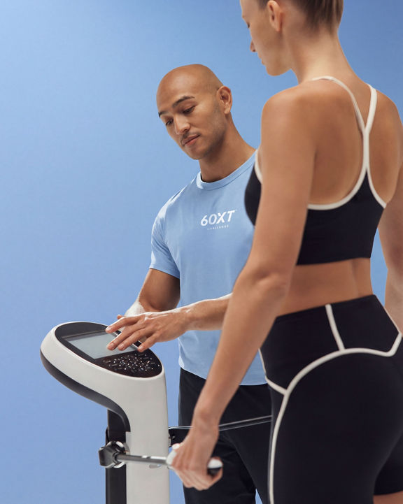 woman standing on a scale while trainer measures her weight