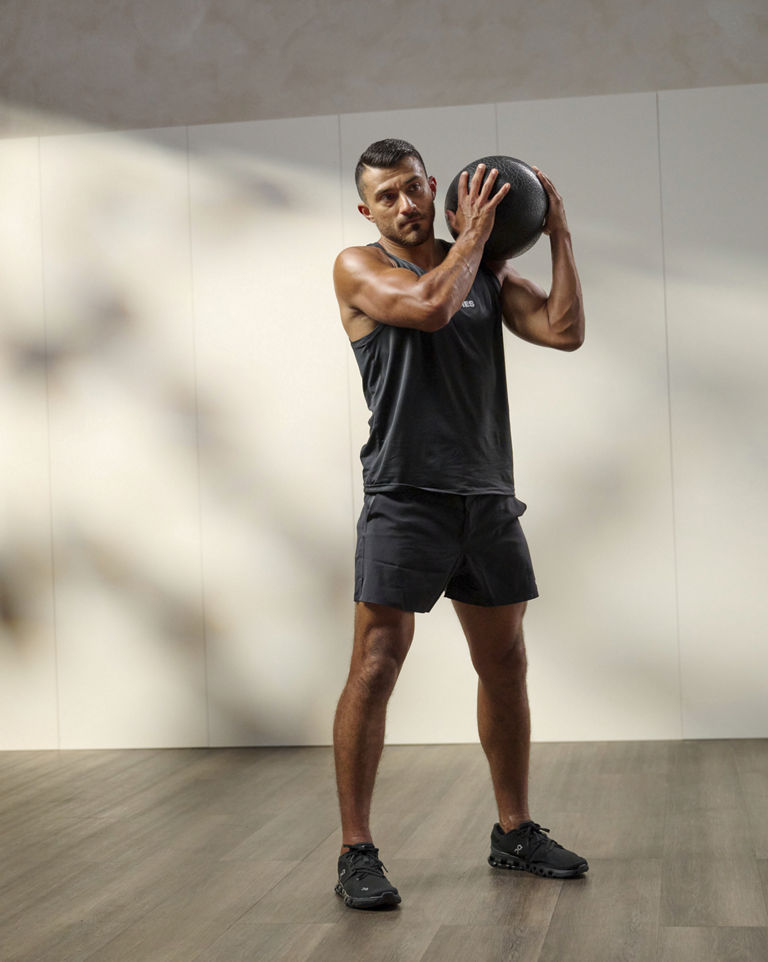 a man putting a medicine ball over his shoulders