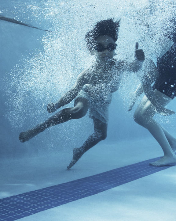 a kid jumping into a swimming pool