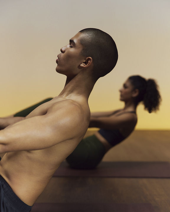 Yogis in boat pose during HIIT fire yoga class at Life Time