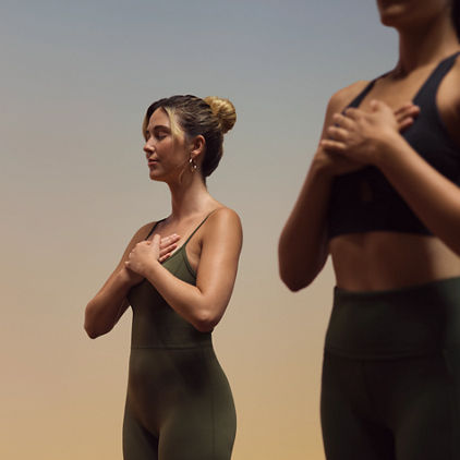 Yogis in hands to heart pose during fire yoga class at Life Time
