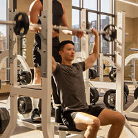 A man spotting another member while he completes overhead presses while seated on a weight bench