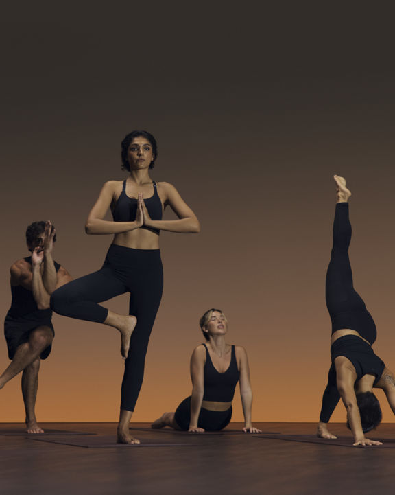 Group of six people in varying yoga poses at a flow yoga class