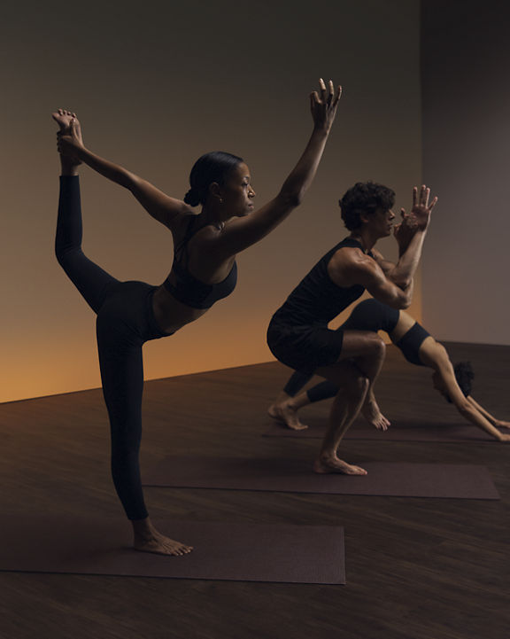 Three people in varying poses at a Life Time flow yoga class