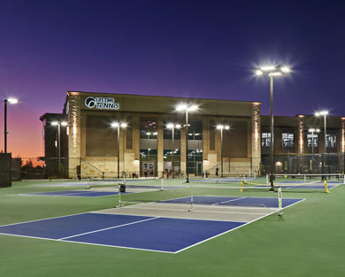 3 outdoor pickleball courts outside a Life Time at dusk