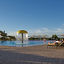 a young girl runs into an outdoor pool complete with mushroom waterfall, lap pool, waterslides, and surrounded by lounge chairs