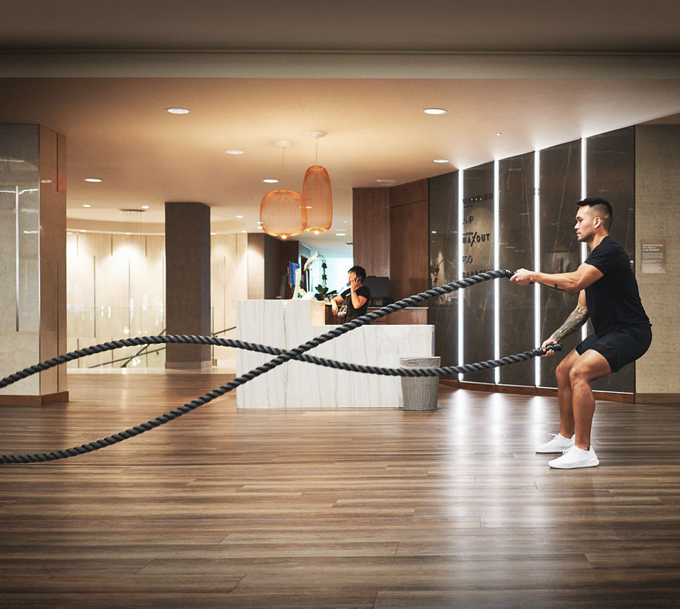 A Life Time member using battle ropes on the fitness floor