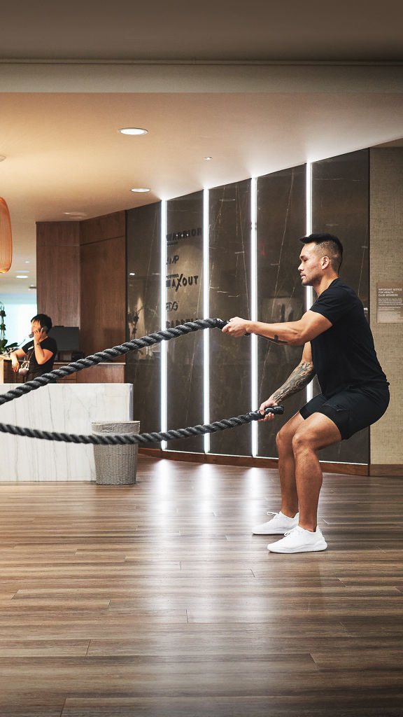 A Life Time member using battle ropes on the fitness floor