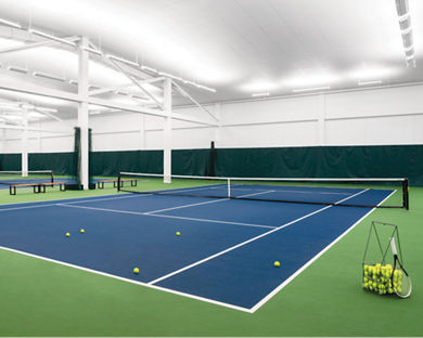 Indoor tennis courts, with a basket of tennis balls, at a Life Time location