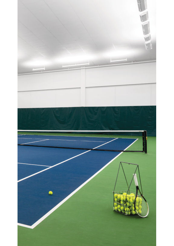 Indoor tennis courts, with a basket of tennis balls, at a Life Time location