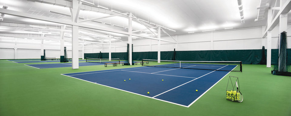 Indoor tennis courts, with a basket of tennis balls, at a Life Time location