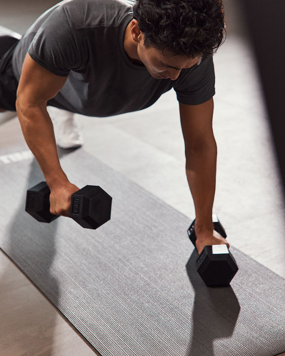 GTX class member in plank position lifting hand weights