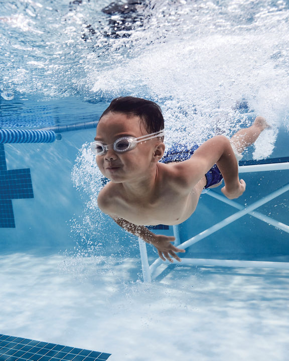A young boy swims underwater in a pool