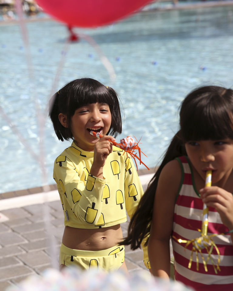 Young children celebrating a birthday by an outdoor pool at Life Time