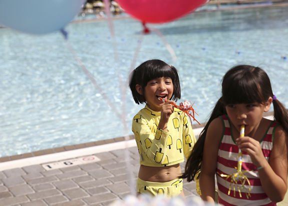 Young children celebrating a birthday by an outdoor pool at Life Time