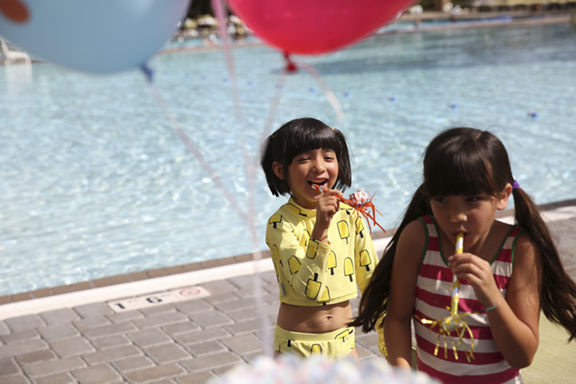 Young children celebrating a birthday by an outdoor pool at Life Time