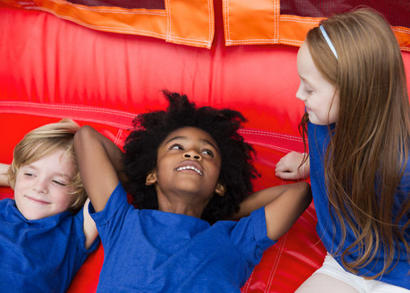 Three kids rest on a blow up bouncy house