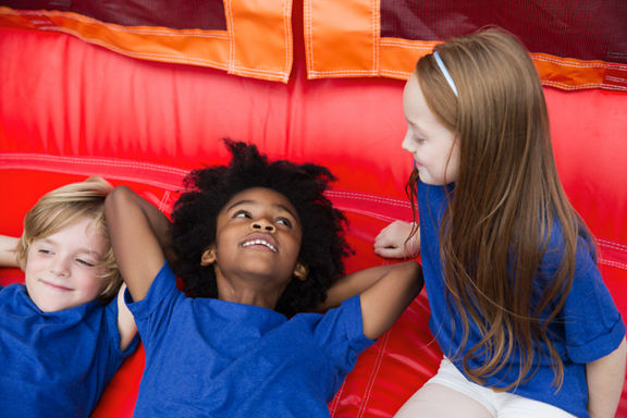 Three kids rest on a blow up bouncy house