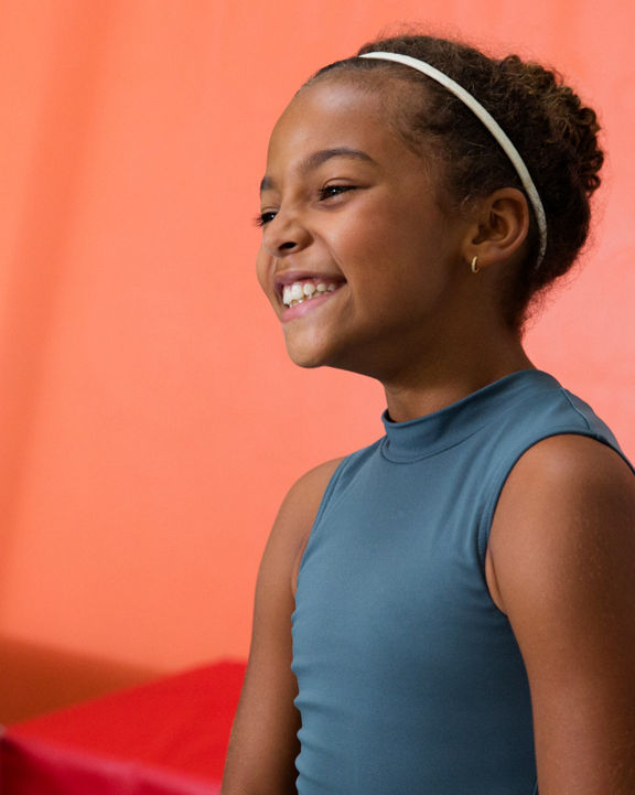 Portrait of a young girl smiling with tumbling mats behind her