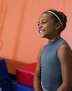 Portrait of a young girl smiling with tumbling mats behind her