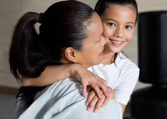 A woman and a female child embrace each other in a karate studio