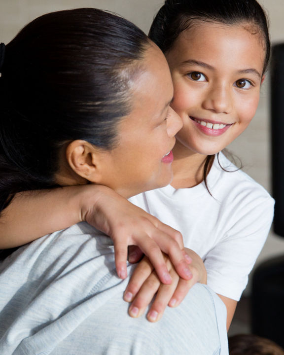 A woman and a female child embrace each other in a karate studio