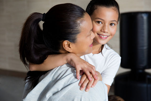 A woman and a female child embrace each other in a karate studio