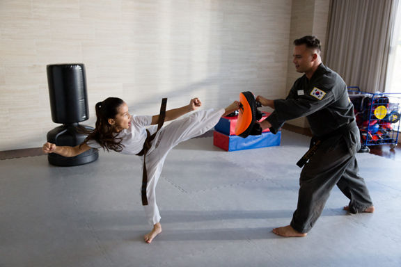 A female child and a male karate teacher practice karate moves in a fitness studio