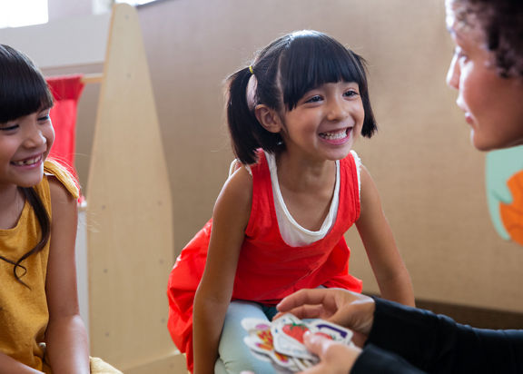 A teacher and two children sit on the floor at Life TIme Kids Academy