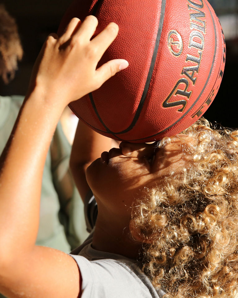 A young child holding a basketball above their head