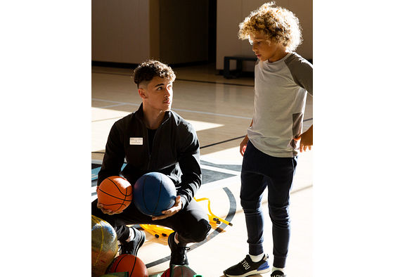 a boy learning basketball from an instructor
