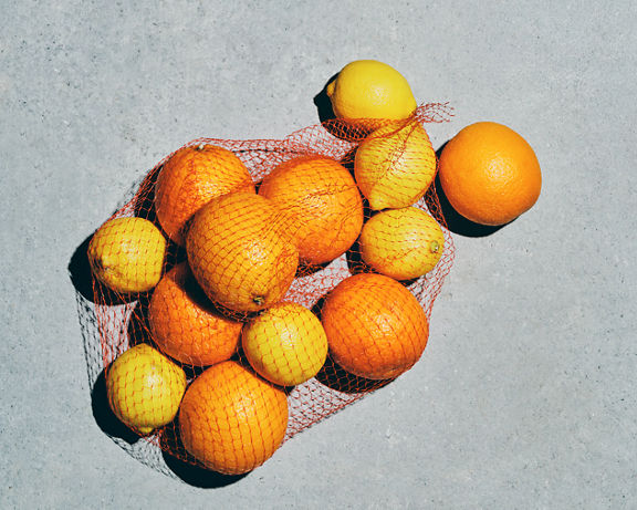 Overhead view of lemons and oranges in a plastic netted bag