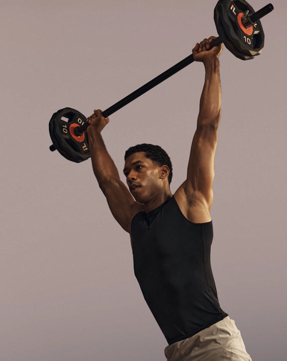 Life Time member lifting a barbell overhead in a strength class