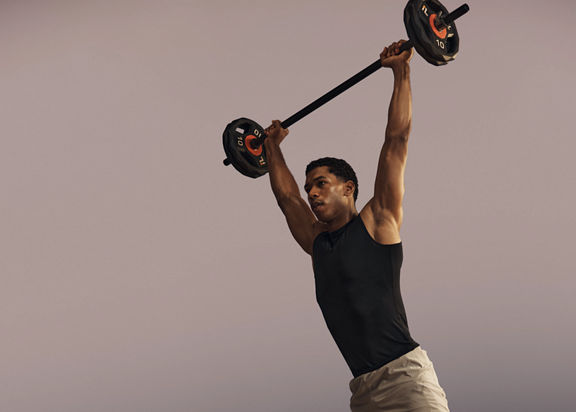 Life Time member lifting a barbell overhead in a strength class