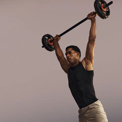 Life Time member lifting a barbell overhead in a strength class