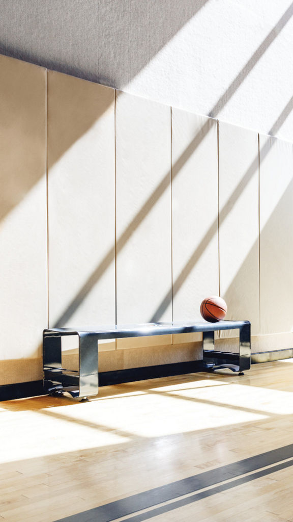 A bench with a basketball on it, in a brightly lit gymnasium