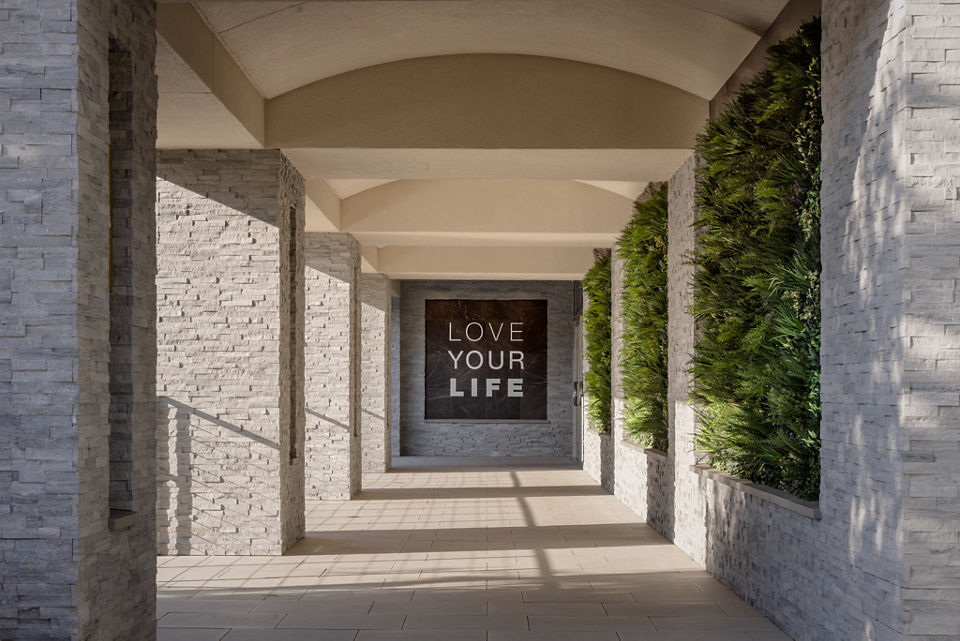 Outdoor hallway and Love Your LIfe Signage with green plant wall at the LIfe Time Lakeshore Irvine club location