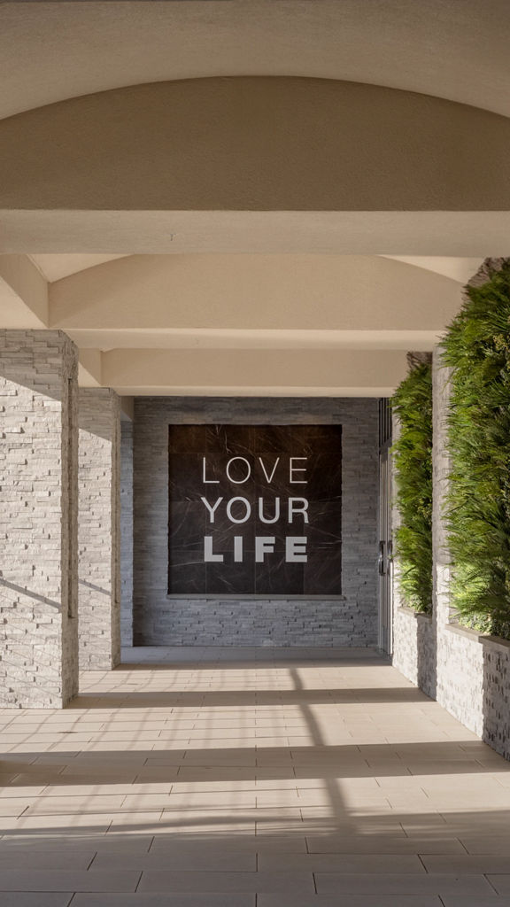 Outdoor hallway and Love Your LIfe Signage with green plant wall at the LIfe Time Lakeshore Irvine club location