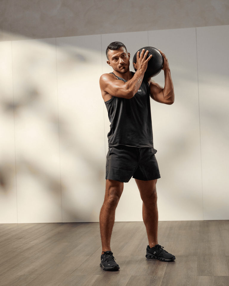 a man throwing a medicine ball over his shoulder