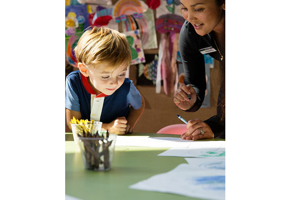 boy drawing a picture with a Life Time team member