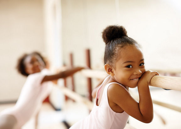 little girl holding onto a ballet bar