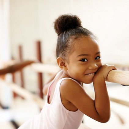 little girl holding onto a ballet bar