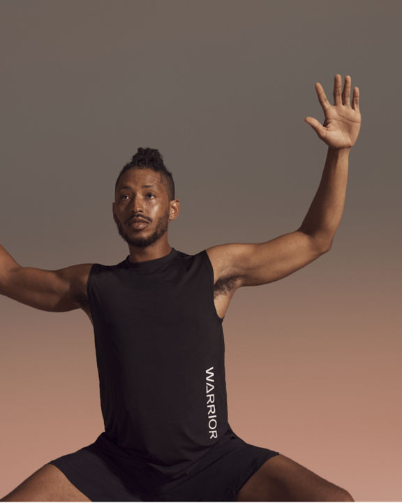 Yogi with raised arms in deep squat position during warrior sculpt class at Life Time