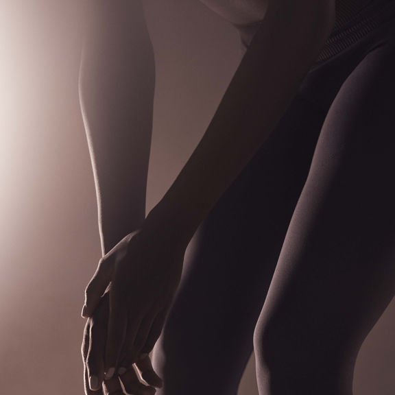 woman bending over cupping her hands by her knees