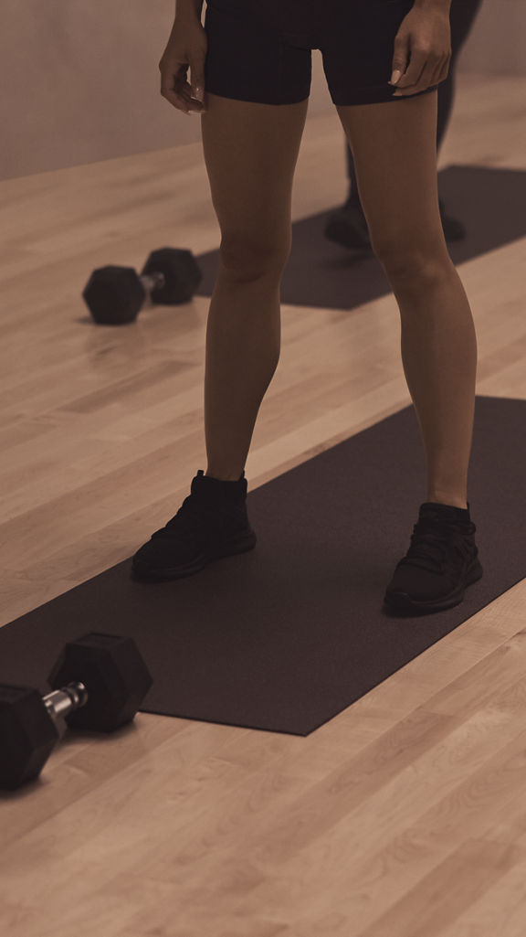 The feet of four Life Time members on their mats at a MB360 boutique group training class