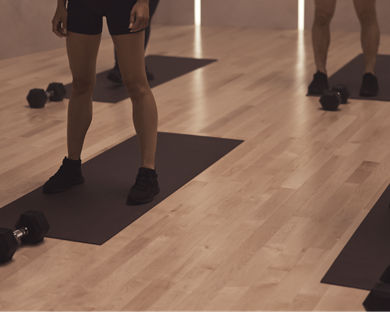 The feet of four Life Time members on their mats at a MB360 boutique group training class