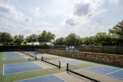 Pickleball courts at the club, surrounded by greenery, located at the edge of a serene landscape.