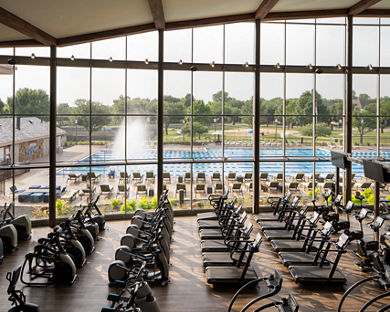 Fitness floor at Life Time McKinney at Craig Ranch looking out at the outdoor pool