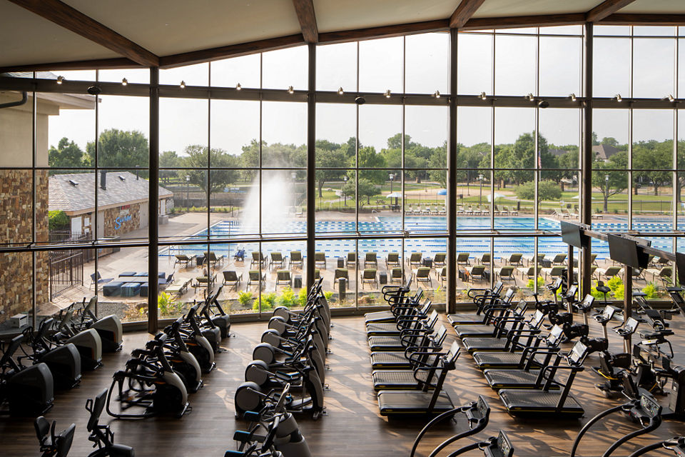 Fitness floor at Life Time McKinney at Craig Ranch looking out at the outdoor pool